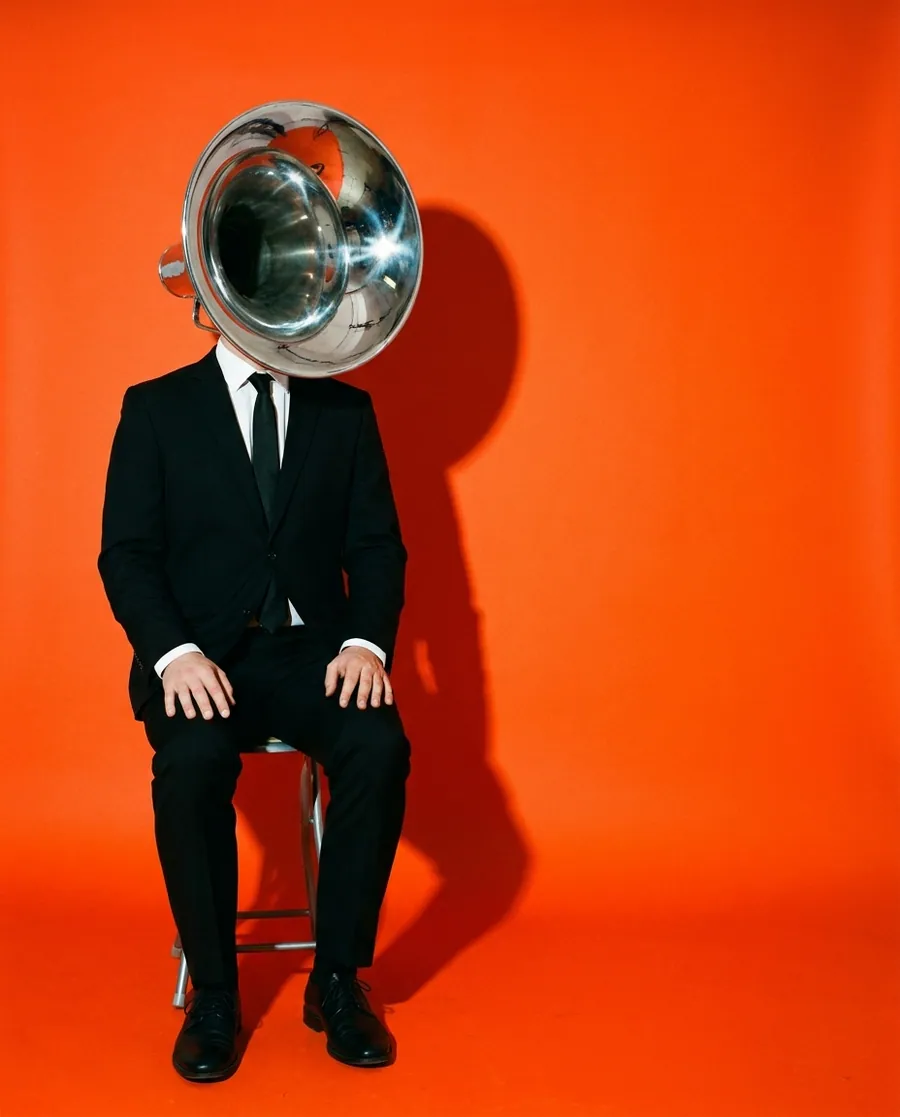 A man whose head is a megaphone on a vermilion field